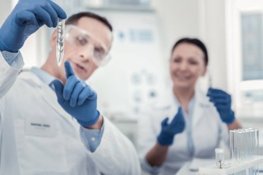 Bir üretim tesisi ile test tüpü tutan bilim adamı