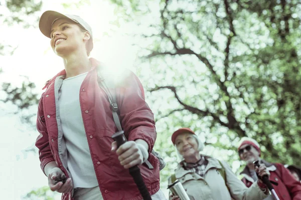 Young hiking guide feeling inspired by elderly tourists — Stock Photo, Image