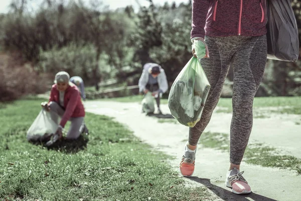 Mujer en zapatos deportivos rosa va con la basura —  Fotos de Stock