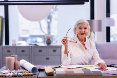 İşkadını gülümseyerek gözlük elinde tutan yıllarda pompalarıgelişmiş