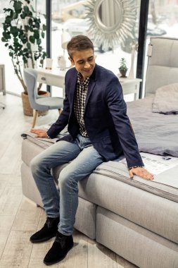 Showroom yatağın kenarında oturan iyi görünümlü şık bayım