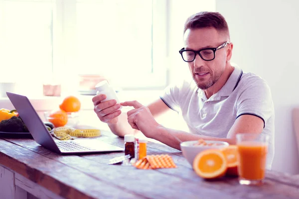 Hombre con gafas leyendo la información sobre suplementos y vitaminas —  Fotos de Stock