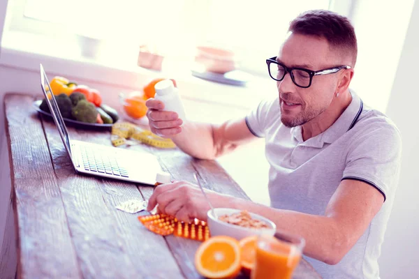 Человек в очках изучает ингредиенты витаминов, имеющих здоровый завтрак — стоковое фото