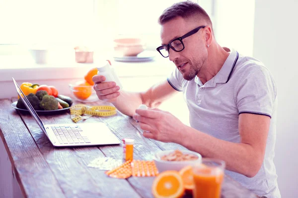 Man leading balanced diet holding his morning vitamins having healthy breakfast