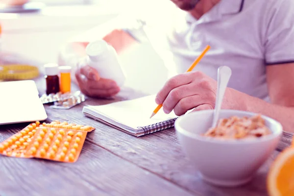 Close up de homem vestindo camisa branca fazendo anotações sobre suplementos alimentares — Fotografia de Stock