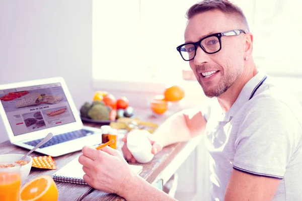 Blonde-haired man wearing glasses taking food supplements sitting on diet