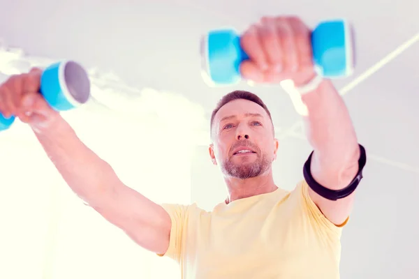 Bearded blue-eyed businessman doing morning exercises with hand weights — Stock Photo, Image