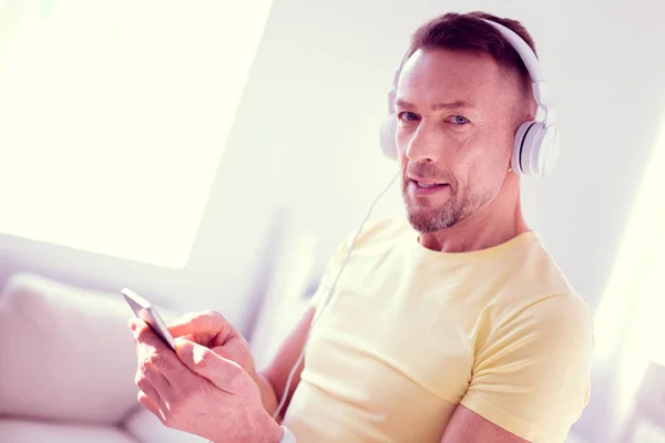 Hombre guapo de ojos azules se siente relajado mientras escucha música usando auriculares — Foto de Stock