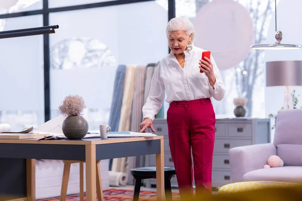 Anciana mujer de negocios elegante de pie en la oficina sosteniendo un teléfono — Foto de Stock