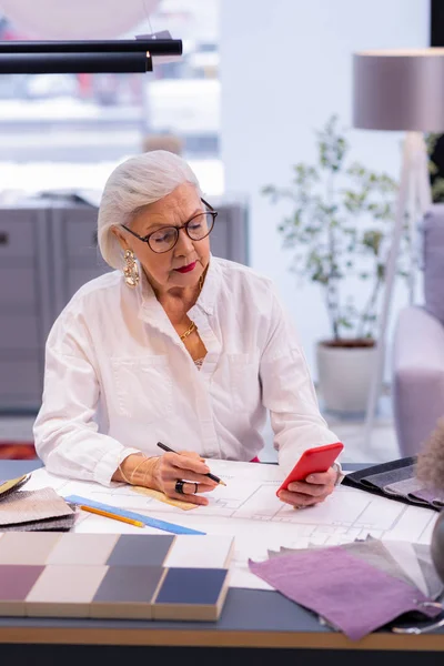 Mujer elegante jefe de policía en años mindfully comprobar su teléfono — Foto de Stock