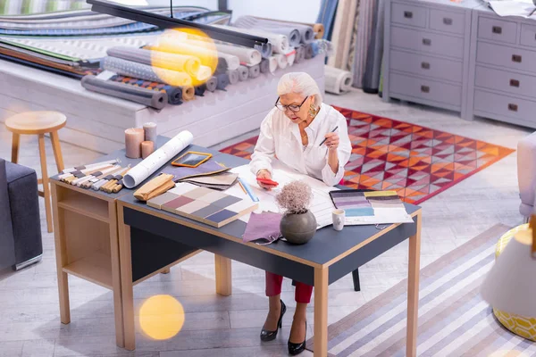 Ocupado chic envejecimiento ejecutivo femenino elegir muestras de tela en la oficina — Foto de Stock