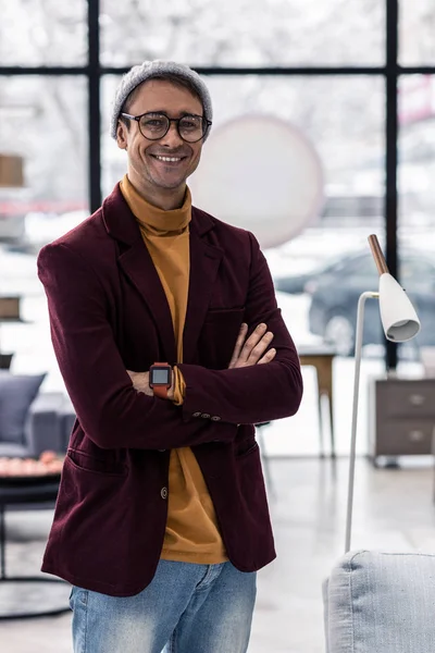 Elegante uomo dai capelli castani sorridente con stoppie luce in piedi in ufficio — Foto Stock