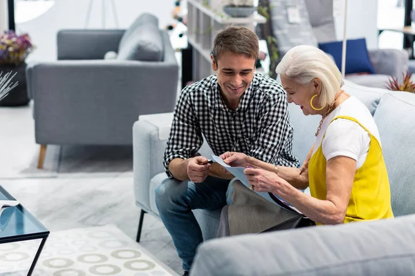 Alluring pleasant gentleman choosing fabric pieces with elderly fashionable mother