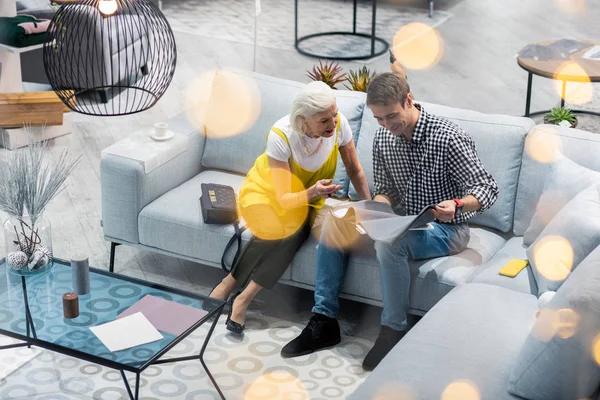 Aged sophisticated dame giving advice about textile choosing to son — Stock Photo, Image