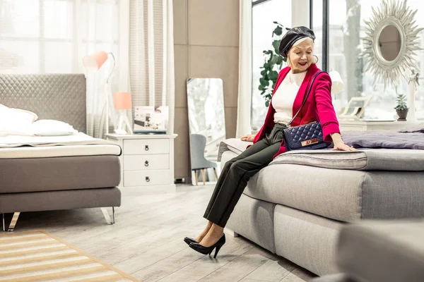 Charming smiling modish dame trying new bed in showroom — Stock Photo, Image