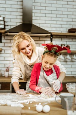 Eğlenerek gülümseyen anne çocuğunu çalışkanlık üzerinde dikkatle seyir