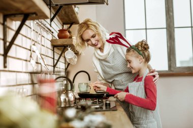 Sarışın anne ve yakın duran kızı gülen gülümseyen