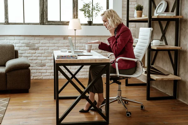Fitte blonde Frau auf Stöckelschuhen löst Geschäftsproblem während eines Telefonats — Stockfoto