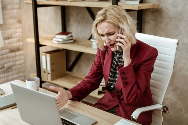 Verwirrte blonde erwachsene Dame im Umgang mit unprofessionellem Verhalten bei der Arbeit — Stockfoto