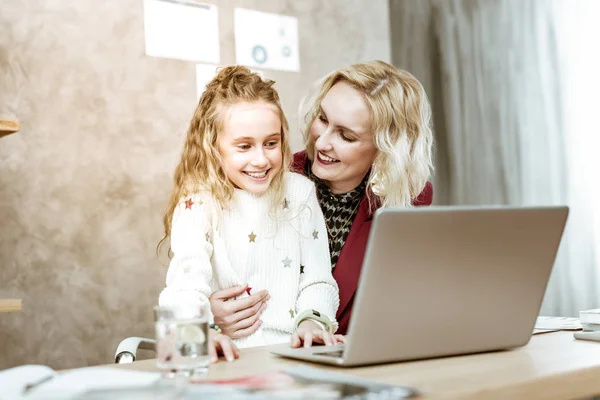 Riendo niña de pelo largo que está interesada en el trabajo de su madre —  Fotos de Stock