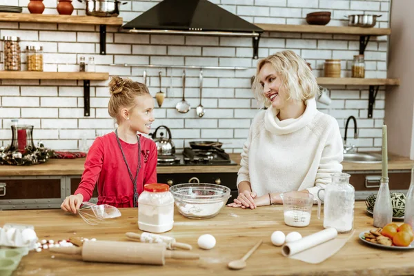Rozpromieniony krótkowłose matka siedzi na kuchni w białym swetrze — Zdjęcie stockowe