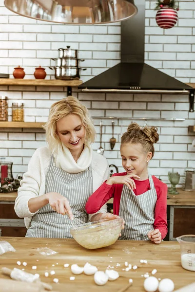 Gotowania uśmiechający się matka i jej córka o bałagan na gotowanie tabeli — Zdjęcie stockowe