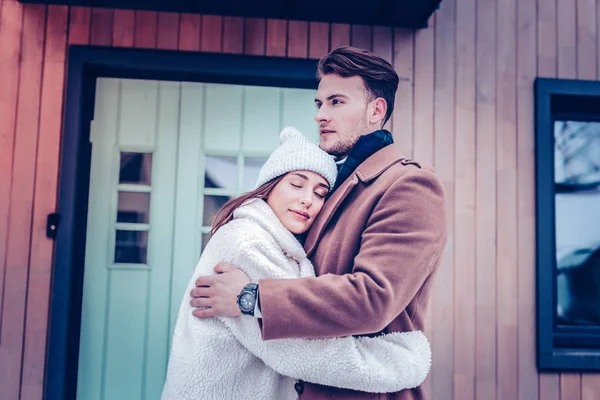 Young stylish girlfriend feeling protected while hugging her man