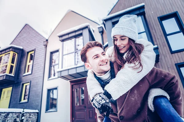 Cute lovely wife jumping on back of her strong handsome husband — Stock Photo, Image