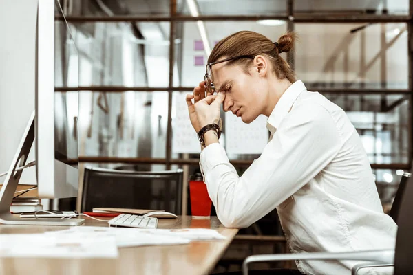 Leuke jonge man houden een brug van zijn neus — Stockfoto