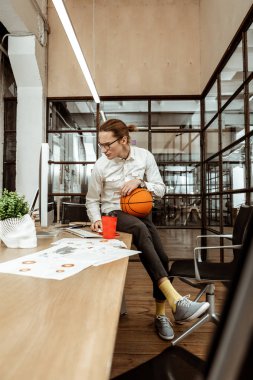 Bir basketbol topu tutan ciddi genç adam