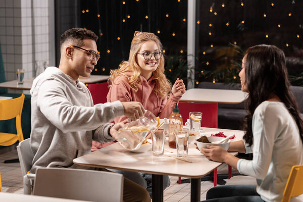 Company of students discusses previous day in university cafe.