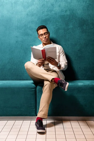 Joven afroamericano sentado y sumergido en libro de lectura . — Foto de Stock