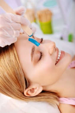 Mavi depilatory krem istemci yüzüne koydu uzmanı