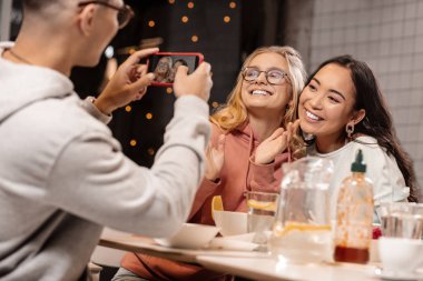 Adam kız arkadaşı ve onun kız arkadaşı telefonda fotoğraflarını gri.