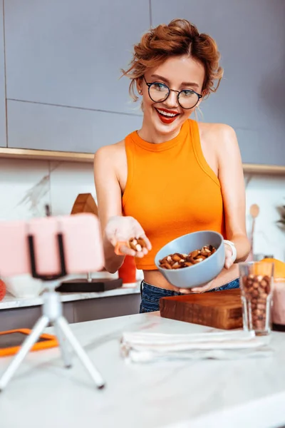 Glad trevlig kvinna håller en handfull nötter — Stockfoto