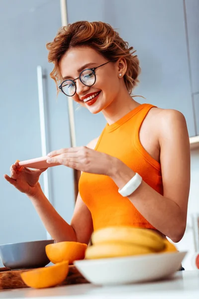 Mujer positiva encantada tomando fotos en su teléfono inteligente — Foto de Stock