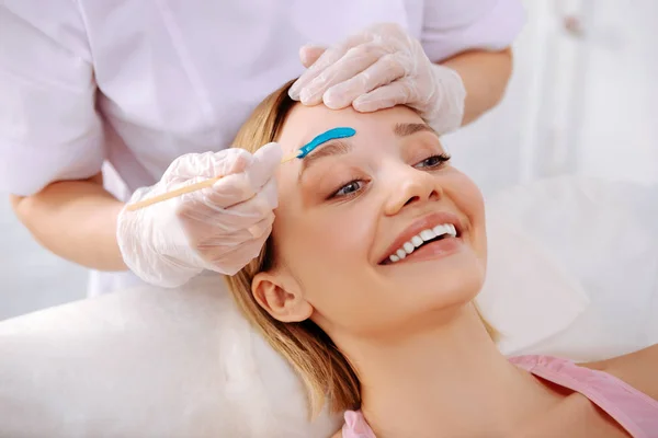 Beaming woman smiling enjoying beauty service in salon