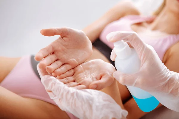 Especialista en desinfectar las manos del cliente antes de comenzar la depilación — Foto de Stock