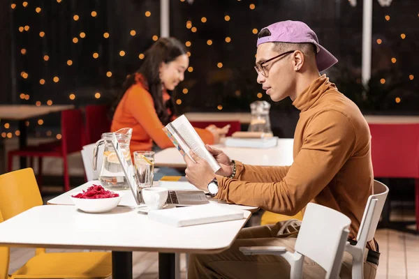 Guy probeert een diner om uit te kiezen het menu in café. — Stockfoto