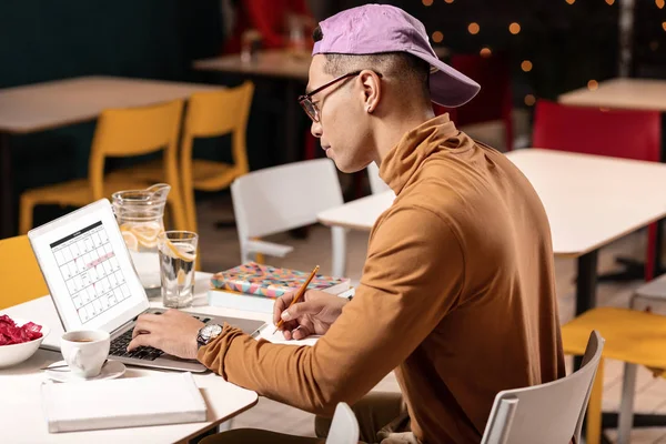 Чоловік сидить за столом і планує графік роботи на тиждень з ноутбуком . — стокове фото