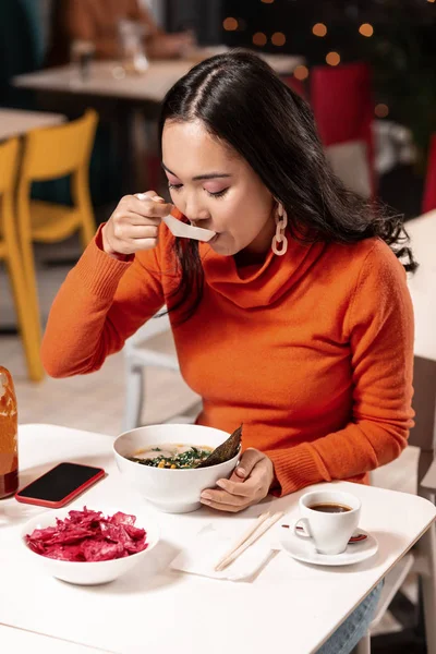 Bevroren Aziatisch meisje warm krijgen door soep in gezellige café. — Stockfoto