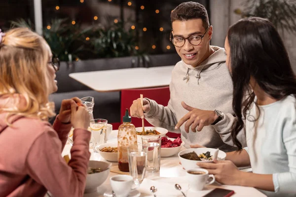 In jonge man bedrijf aanbieden van vrouw om te proberen een nieuwe Aziatische schotel. — Stockfoto