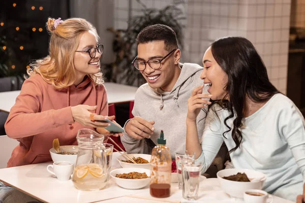 Paar kijken naar de foto's op de telefoon die hun vrouwelijke vriend weergegeven:. — Stockfoto