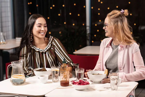 Twee vriendinnen zitten en chatten met enthousiasme in café tijdens de lunch. — Stockfoto