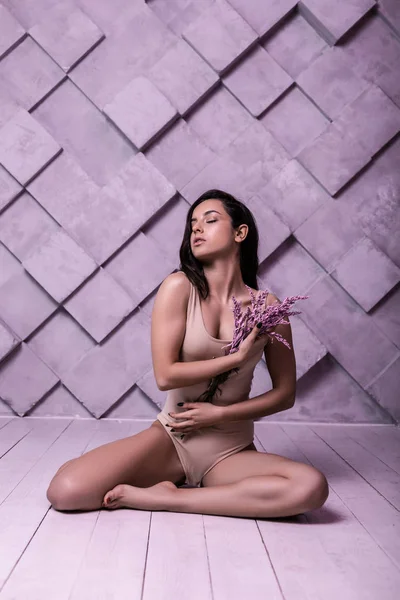 Flirtatious gorgeous lady sitting over lilac background amid photo shooting — Stock Photo, Image