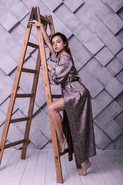 Charming model posing near ladder in the photo shooting process