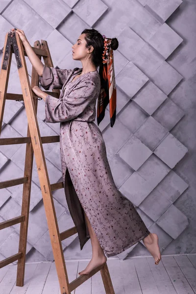 Poste de possession portant une robe debout sur l'échelle pendant le tournage en studio — Photo