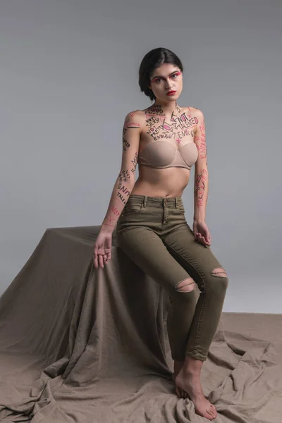 Mörkhårig vacker smal modell i skinny jeans ser ledsen — Stockfoto
