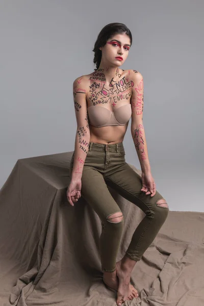 Mörkhårig ganska ung smal modell i jeans visar kroppskonst — Stockfoto