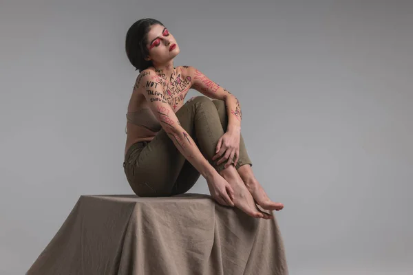 Langhaariges süßes junges Model mit Körperkunst in einem beigen BH sieht entspannt aus — Stockfoto